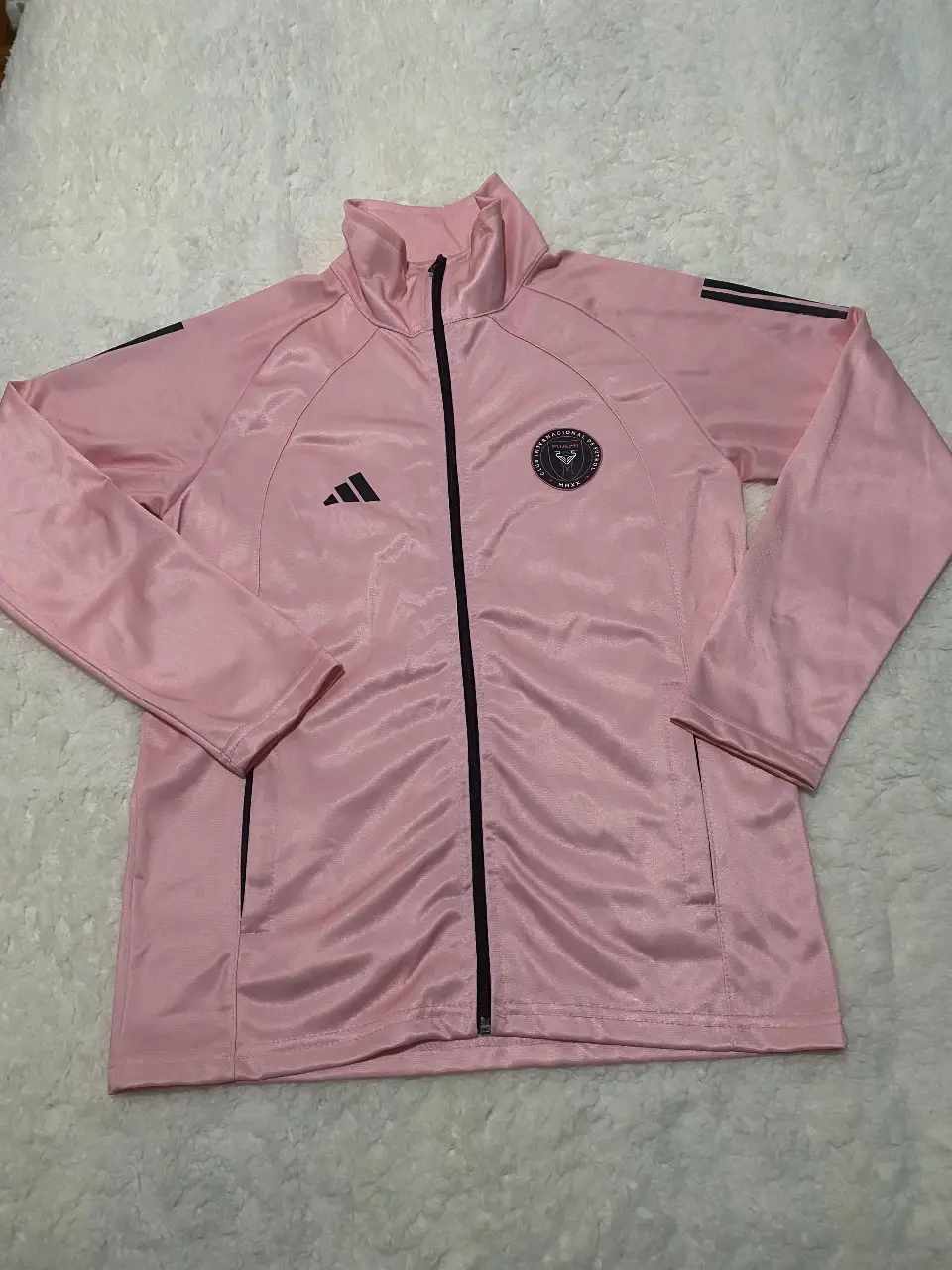 Campera deportiva rosa de hombre, con cierre y logo de Adidas. Ideal para usar en tus entrenamientos o para un look casual.