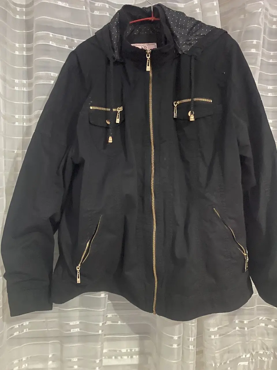 Campera negra con capucha y detalles dorados. Posee cierre frontal y bolsillos con cierre. Interior con diseño de lunares.