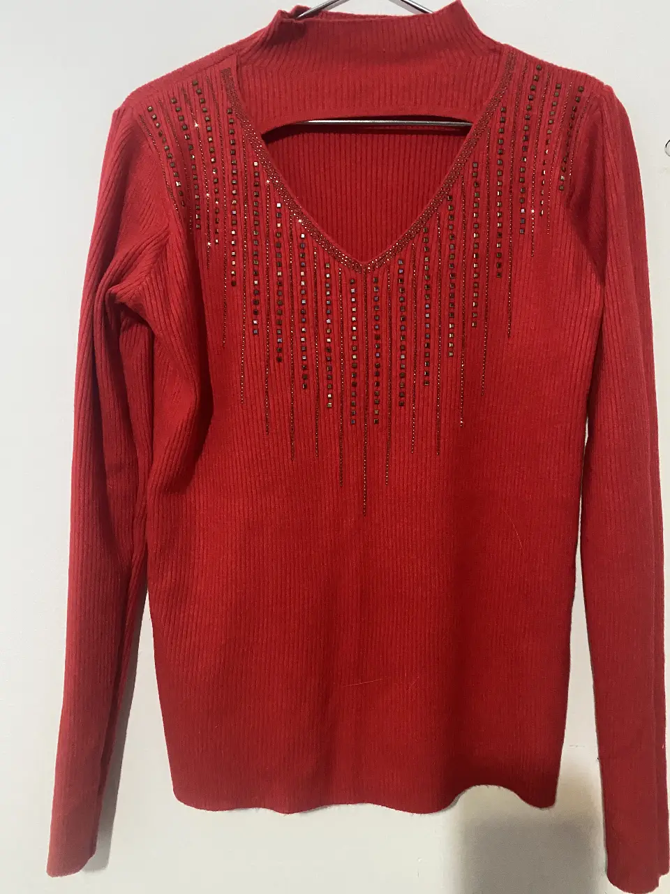 Sweater de cuello alto en color rojo, con detalle de apliques brillantes en el frente. Ideal para un look elegante y abrigado.
