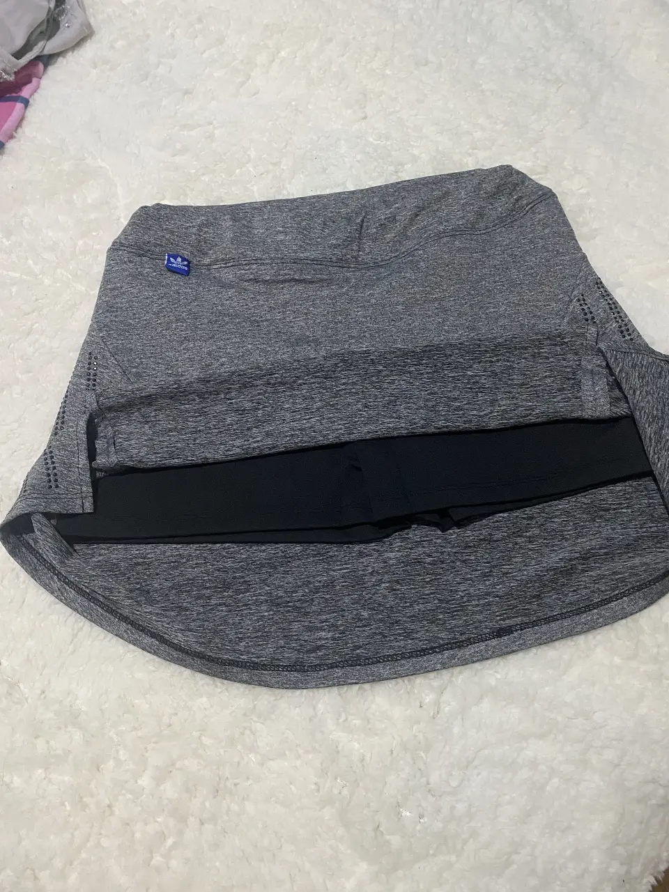 Pollera deportiva Adidas gris con detalles negros. Ideal para entrenamientos y actividades físicas. Diseño moderno y funcional.