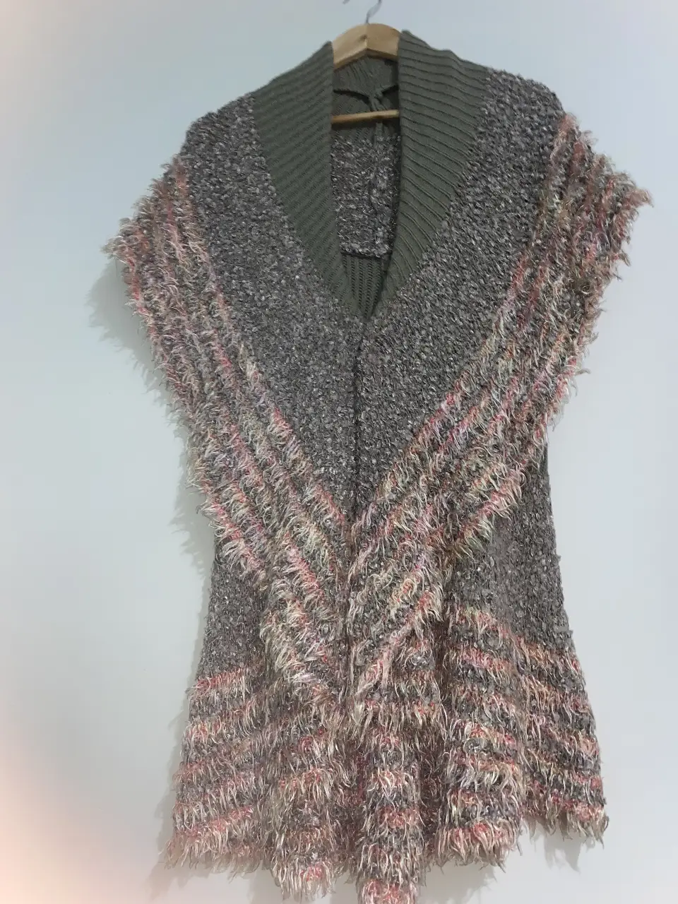 Chaleco tejido con detalles de flecos en tonos grises y rosados. Ideal para un look bohemio y abrigado.