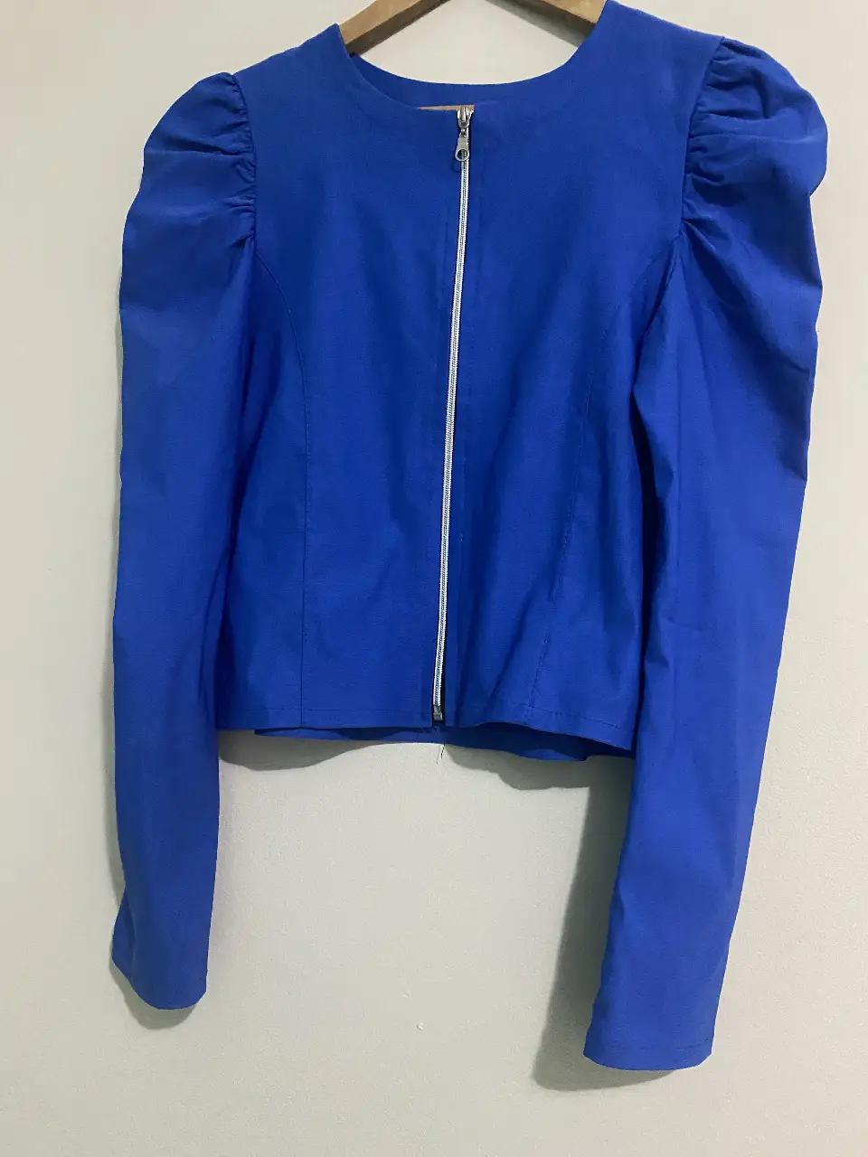 Blusa azul con mangas abullonadas y cierre frontal. Ideal para un look elegante y moderno.