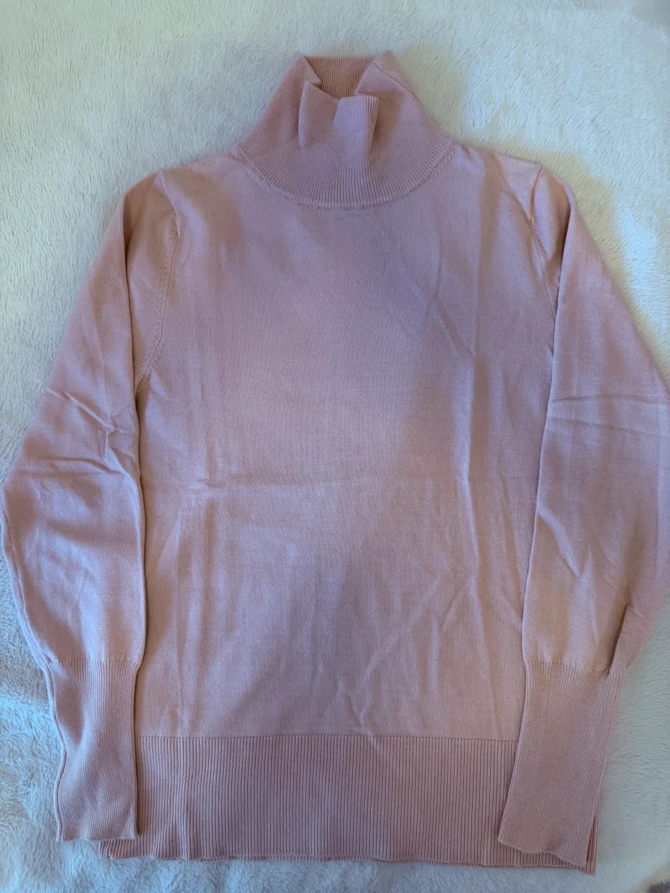 Sweater rosa de cuello alto y manga larga.