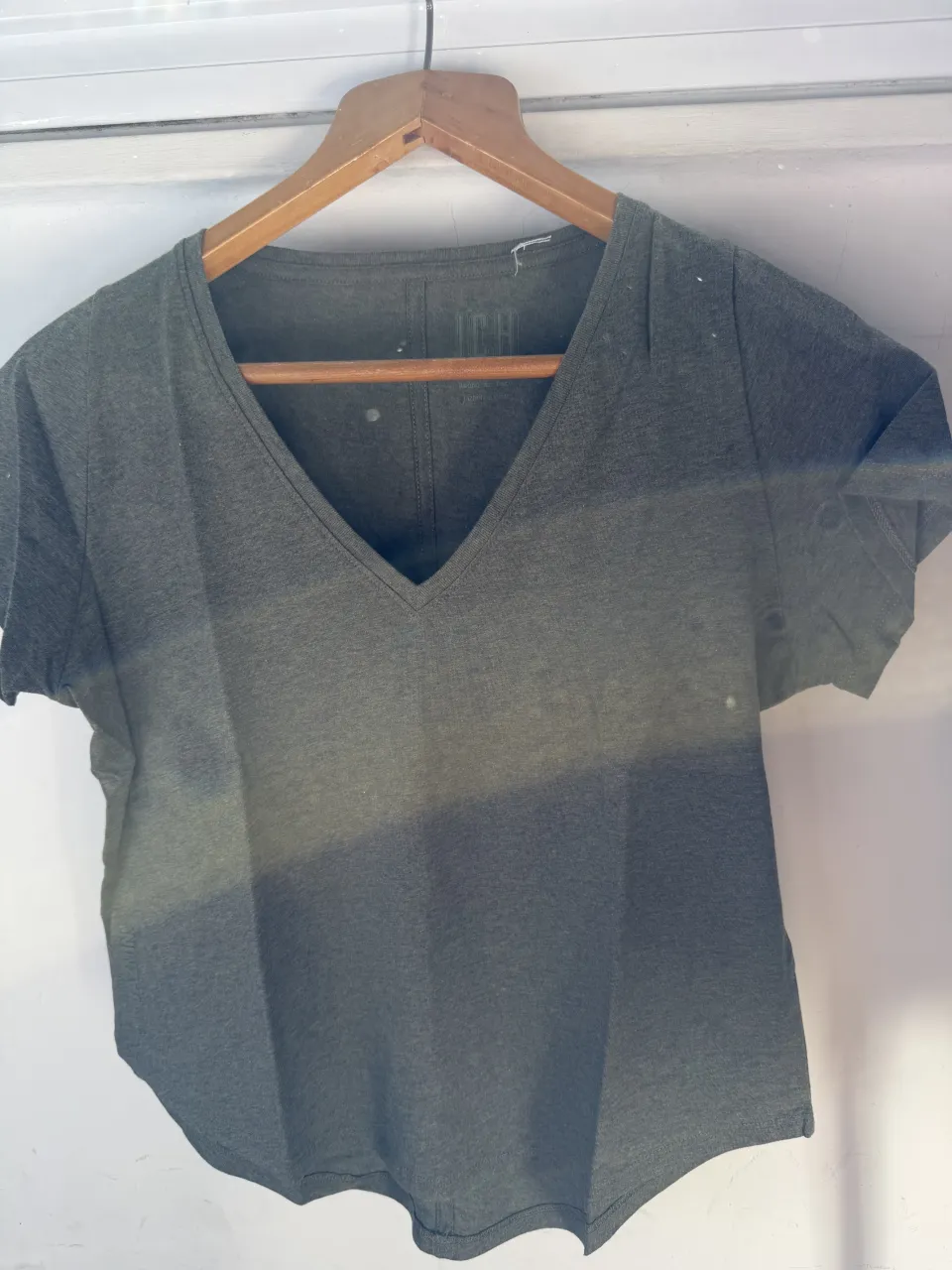 Remera manga corta de algodón color verde musgo con cuello en V. Posee un logo estampado en la parte superior interna y otro en el lateral izquierdo.