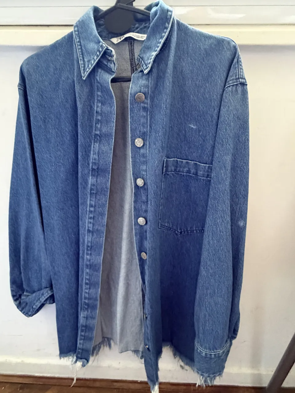 Camisacode debim azul con botones al frente y bolsillo en el pecho. Oversize. Posee detalles deshilachados en puños y ruedo.