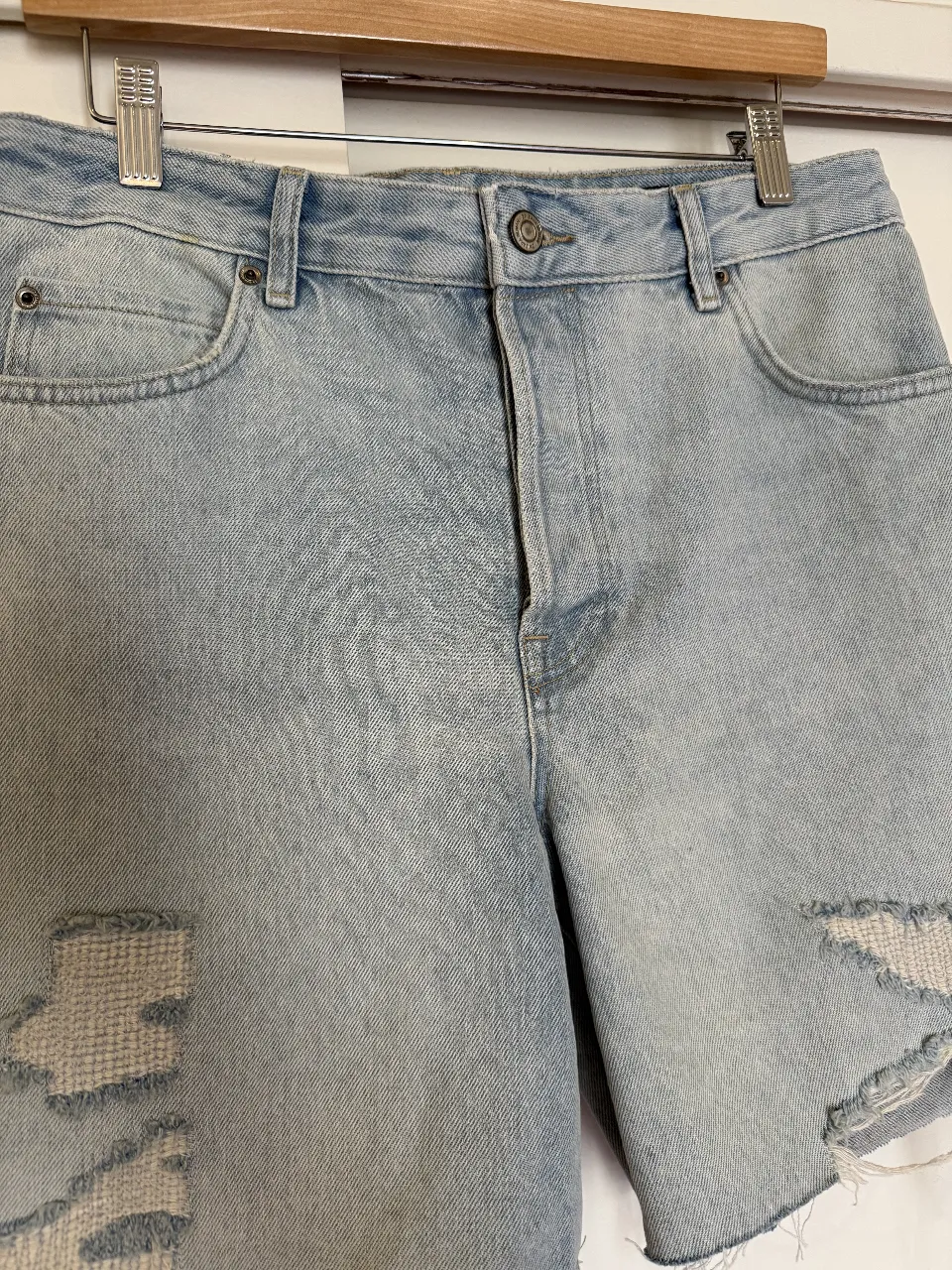 Bermuda de jean de mujer, tiro alto, con roturas y detalles desflecados. Ideal para un look casual y moderno.