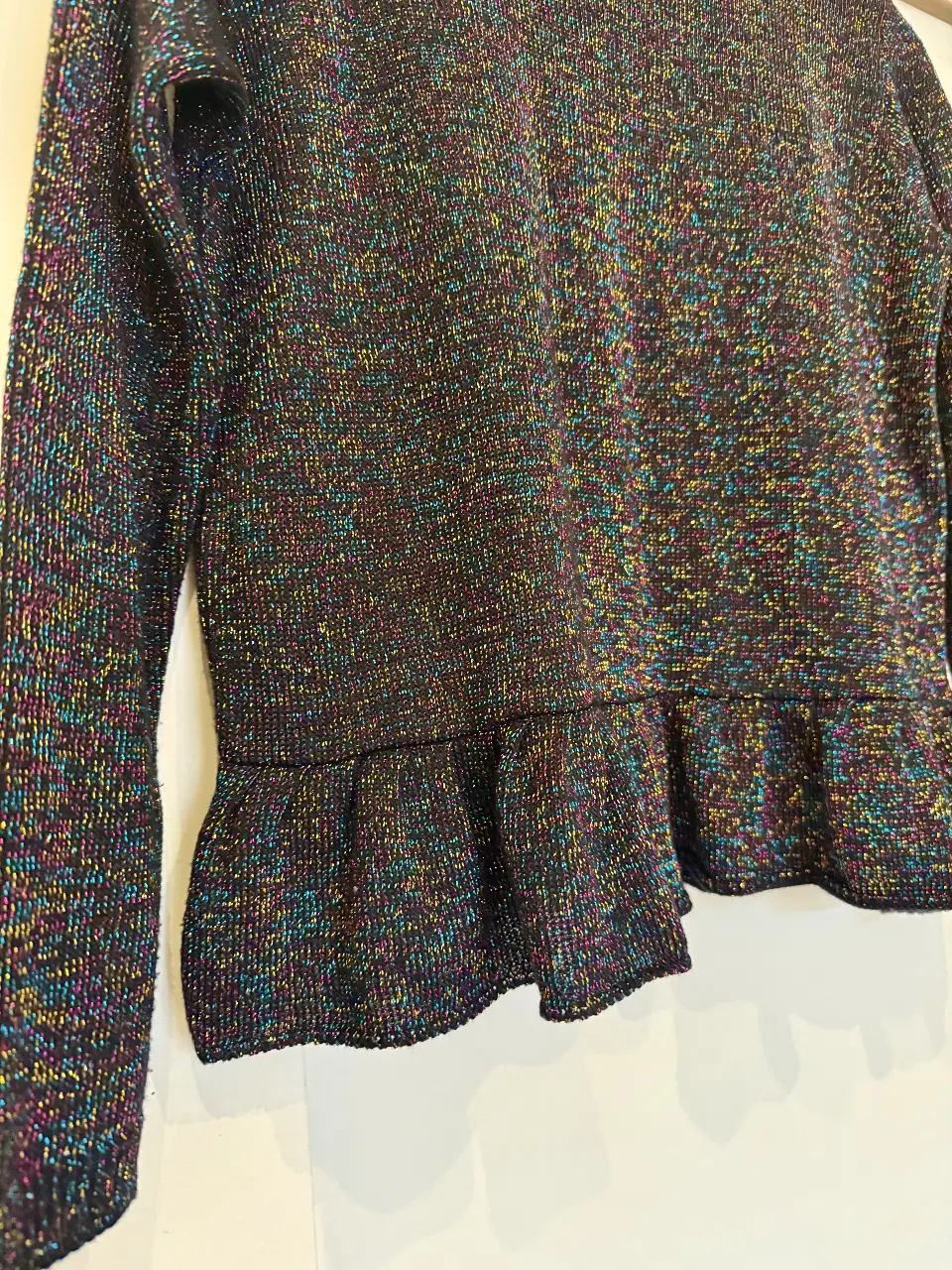 Sweater de mujer con diseño brillante y volados en el bajo. Ideal para un look de fiesta o salida.