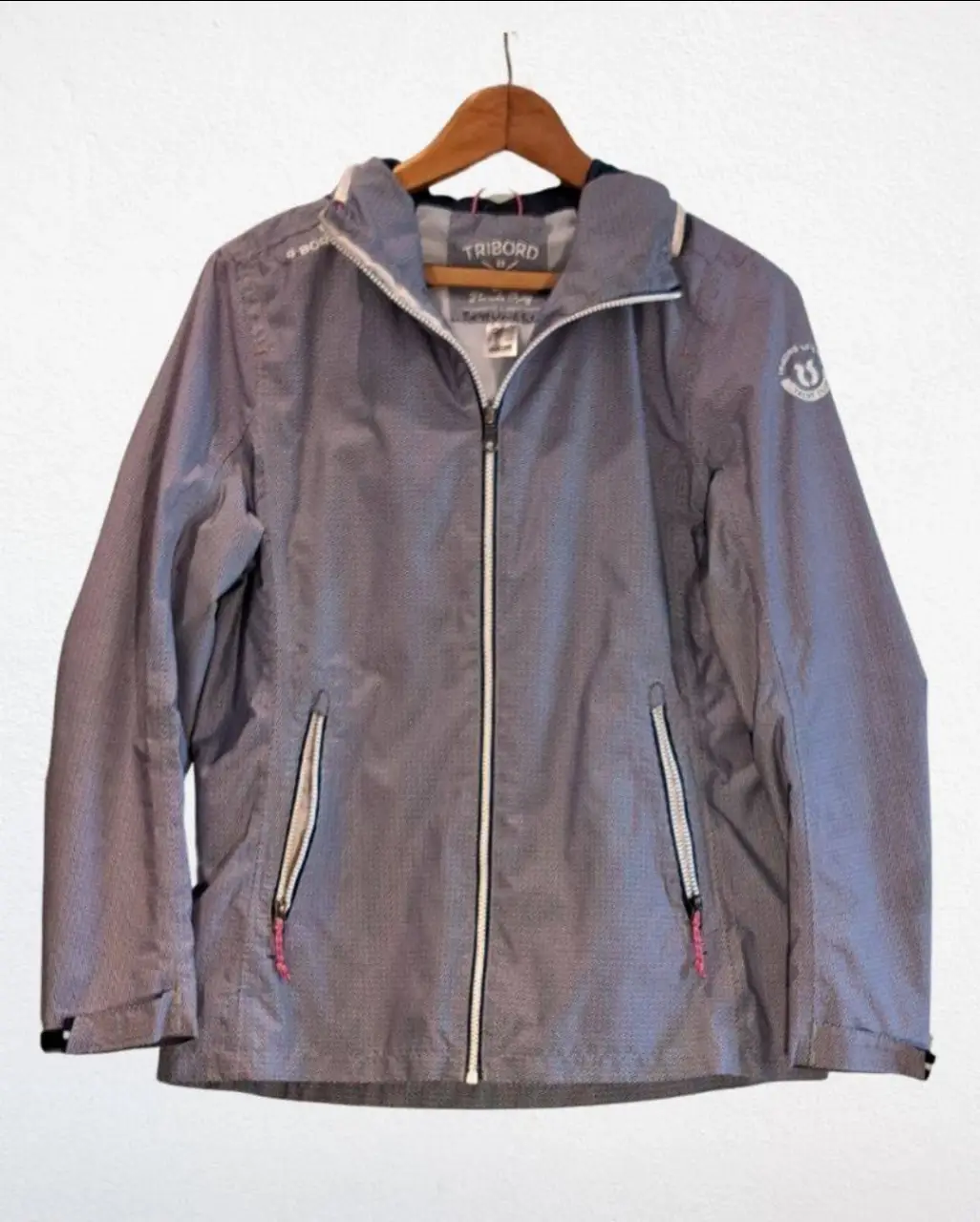Campera deportiva Tribord mujer, con cierre y capucha. Posee bolsillos con cierre y detalles en rosa. Ideal para actividades al aire libre.