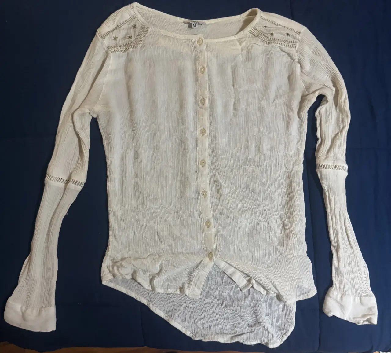 Blusa blanca de manga larga con detalles bordados en los hombros y mangas. Ideal para un look casual y elegante.