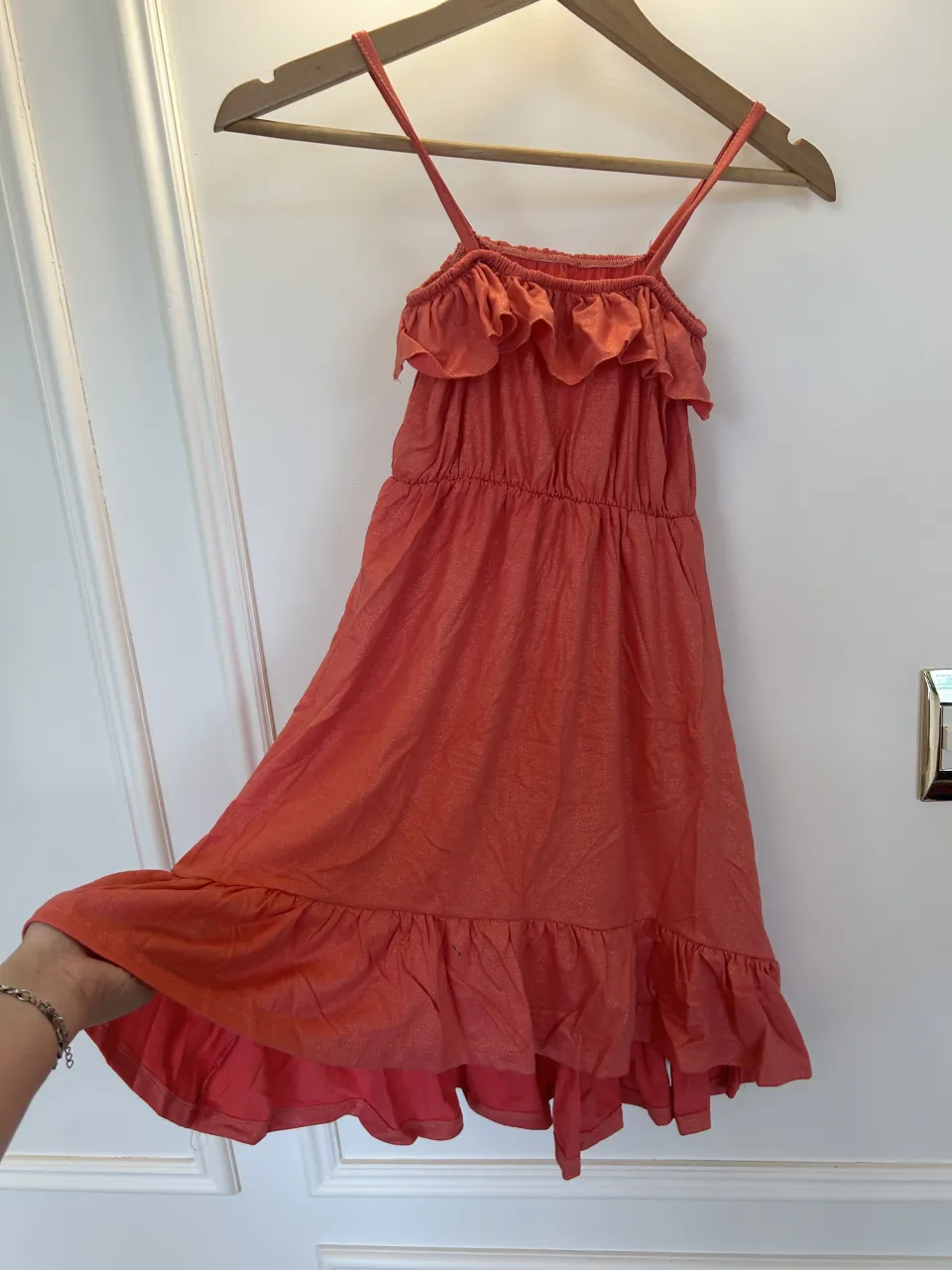 Vestido por debajo de las rodillas color salmon. Con tiras finas y volados en el escote y en el ruedo. Posee un elástico en la cintura.