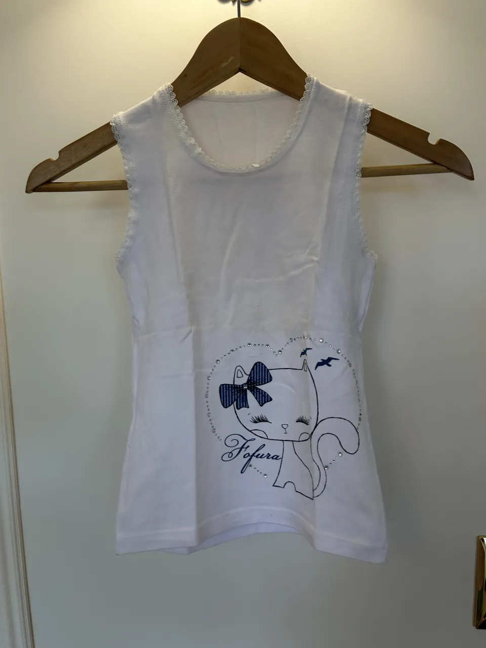 Musculosa blanca con estampa de gatito, moño y pájaros. Detalle de strass alrededor de la estampa. Dice que es talle para niñas de 12, pero yo la utilizaba a los 10, es bastante ajustada.