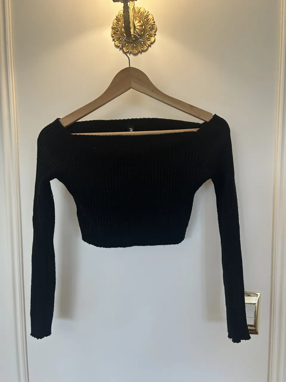 Sweater negro escote barco, manga larga, tejido acanalado.