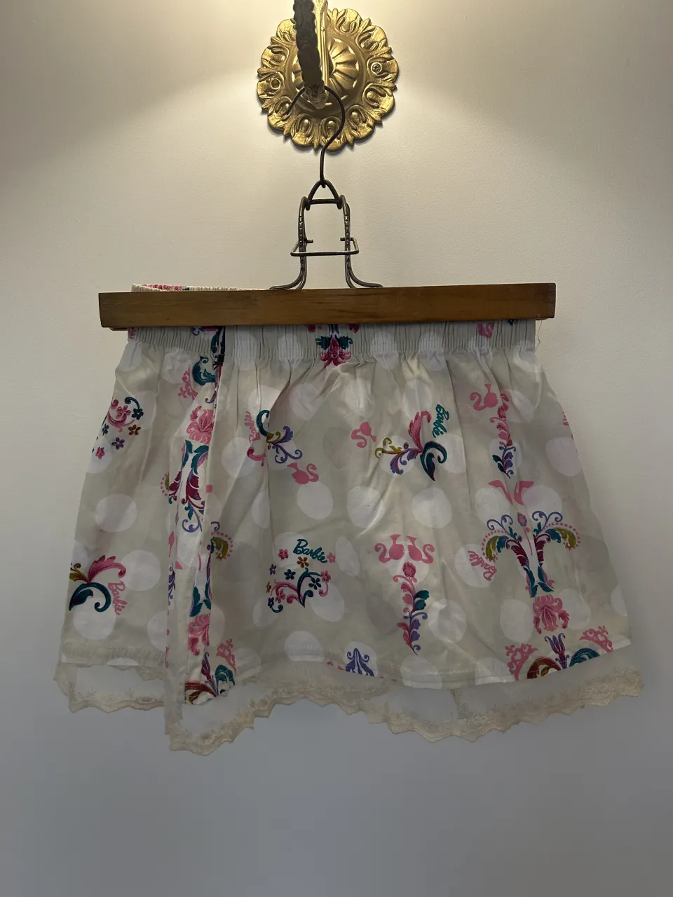 Pollera corta con estampado floral y de lunares. Posee detalles de puntilla en el borde inferior.