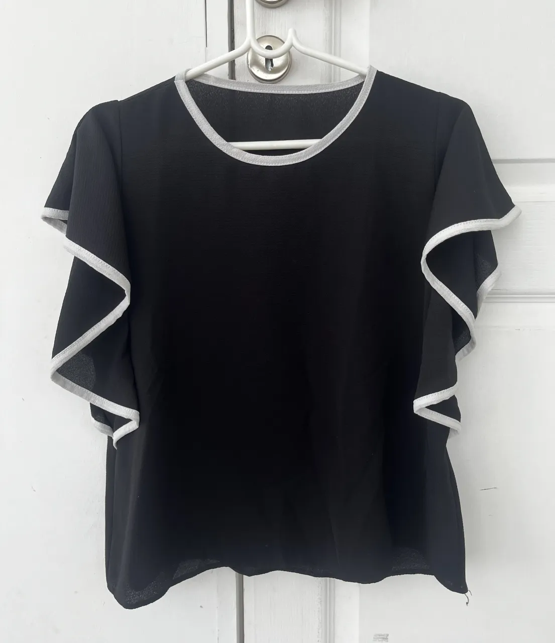 Remera negra con mangas cortas tipo mariposa y detalles en los bordes. Ideal para un look casual y elegante.