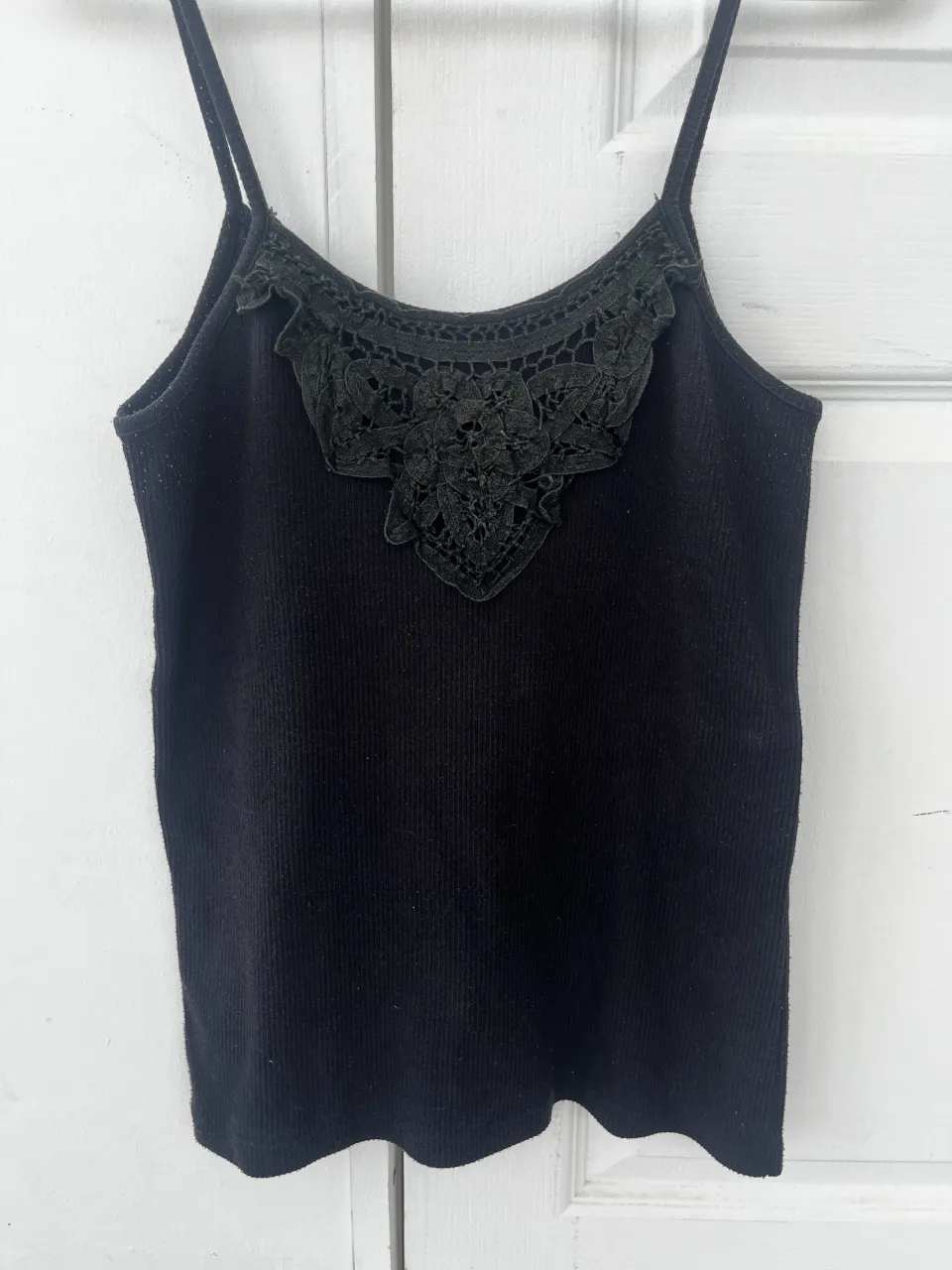 Musculosa negra con detalles de encaje en el escote. Perfecta para un look canchero y femenino.