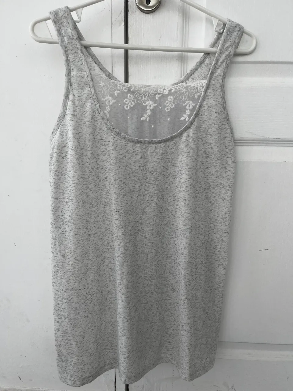 Musculosa gris jaspeado con detalles de encaje floral en la espalda. Perfecta para un look casual y cómodo.