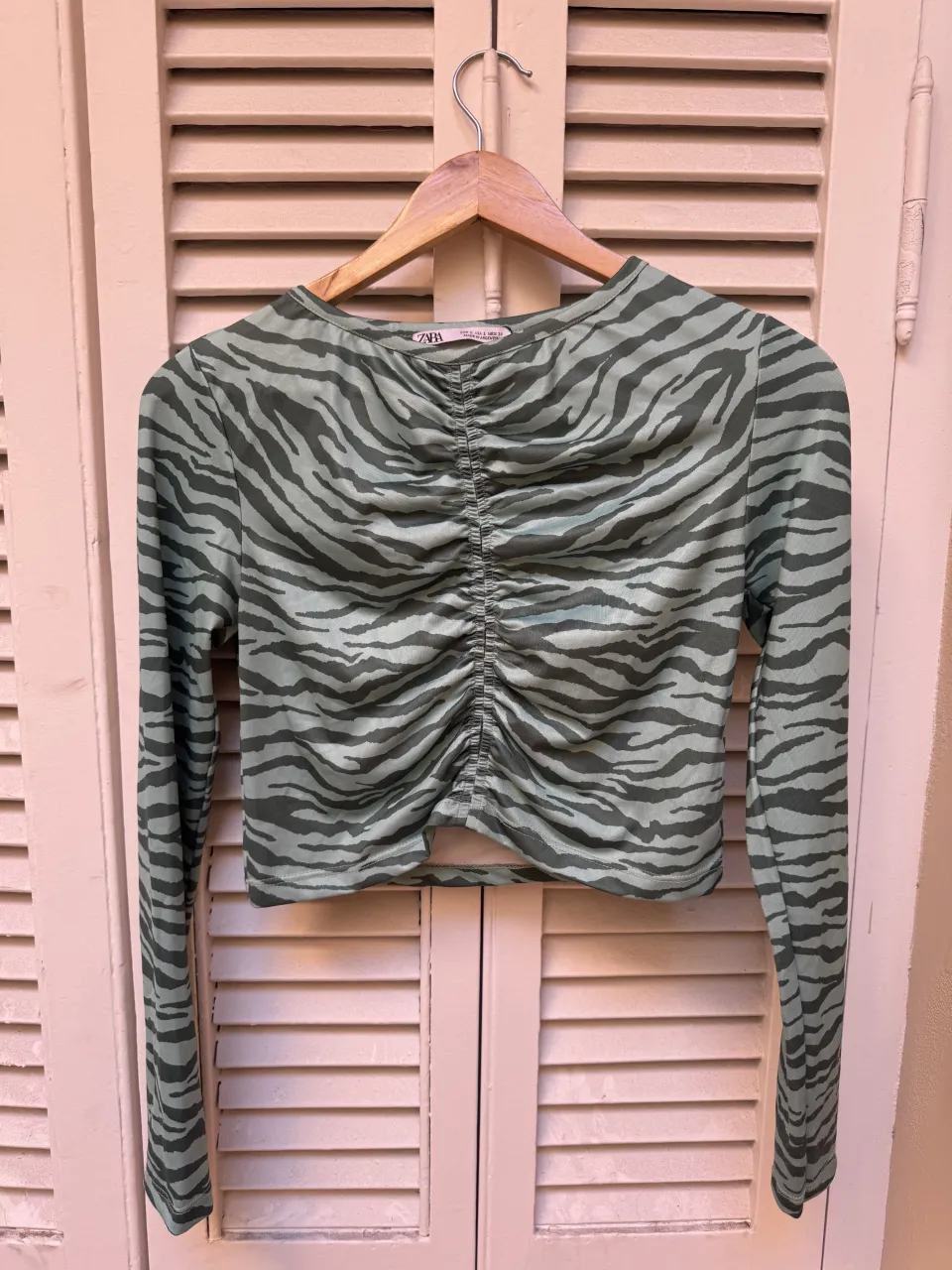 Remera manga larga con estampa de cebra en tonos verdes. Posee un diseño fruncido en el frente que le da un toque canchero y moderno. Ideal para un look casual y a la moda.