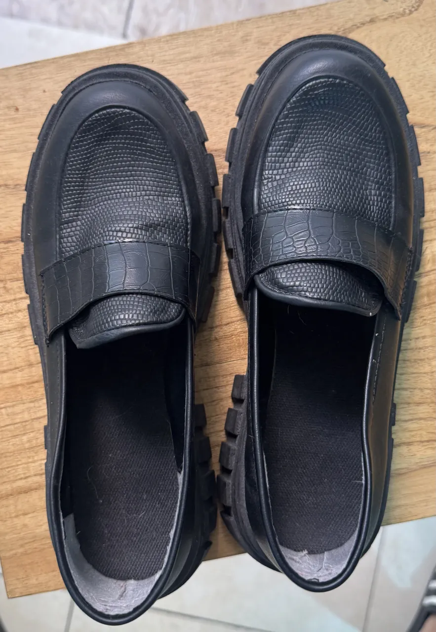 Zapatos mocasines negros con plataforma y detalle de cocodrilo. ¡Un toque moderno y canchero para tu look!