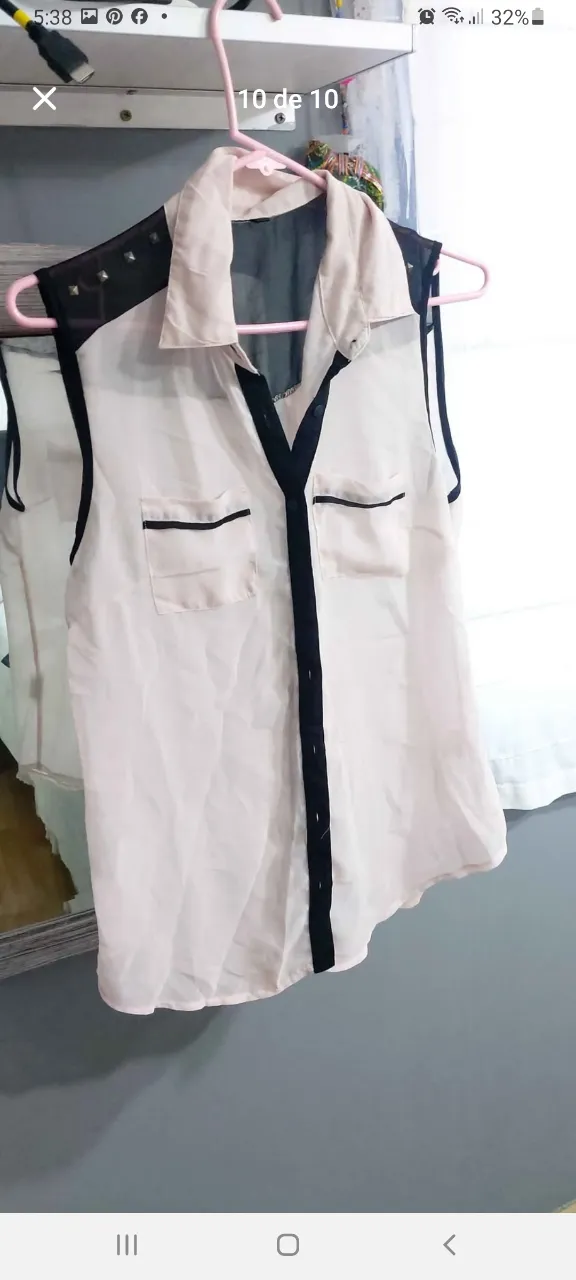 Blusa sin mangas con detalles en negro y tachas en los hombros. Ideal para un look moderno y sofisticado.