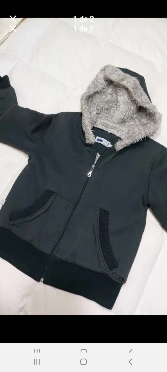 Buzo con cierre negro con capucha forrada en piel sintética gris. Bolsillos delanteros y detalle de la marca Fila en la parte inferior.