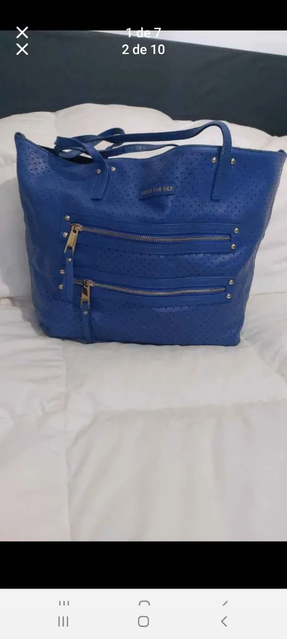 Cartera azul de cuero con detalles de cierres dorados y perforaciones. Ideal para llevar todo lo necesario con estilo.