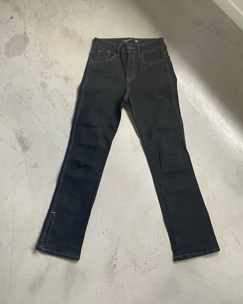 Jean negro con costuras blancas visibles. Posee tajos en los tobillos. Es elastizado, no llega a ser chupin pero queda al cuerpo. Se adapta mucho al cuerpo, calza barbaro. En los pies queda suelto tipo capri. Es tiro alto. Medidas: cintura alta 32cm - cadera 40cm - tiro 26cm - largo 94cm - tobillos 17cm - muslos 21cm