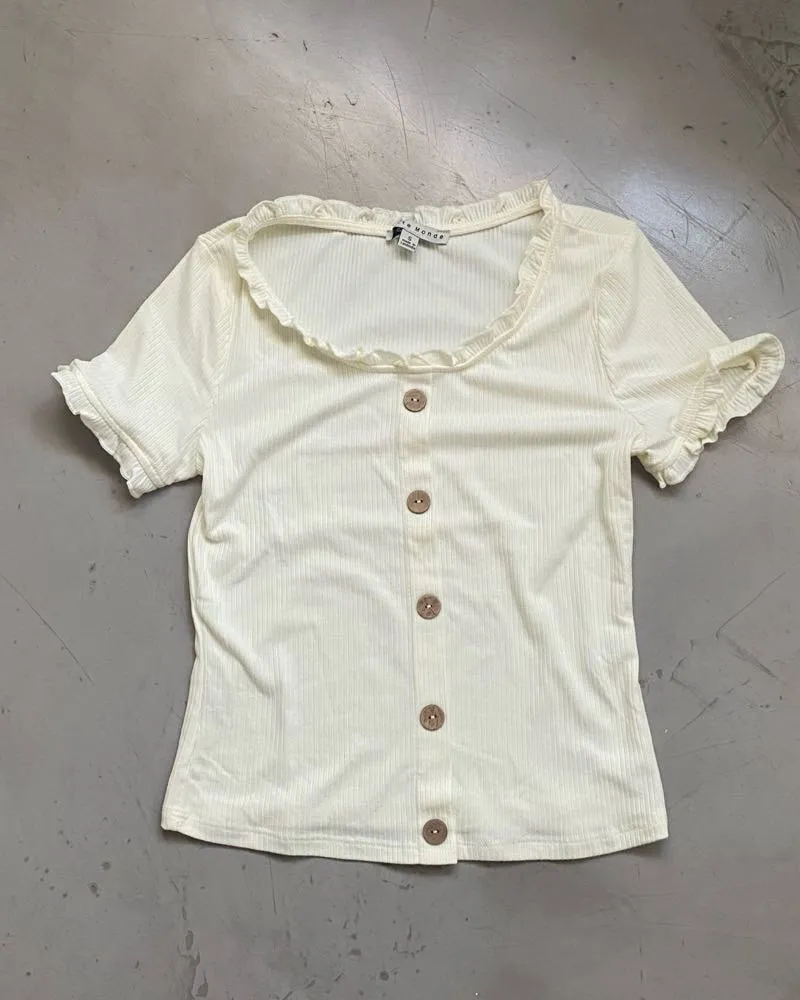 Remera de manga corta con volados y cuello redondo y volados. Posee botones en la parte delantera. Medidas: largo 47cm - axilas 40cm - largo manga 17cm - bicep 13cm