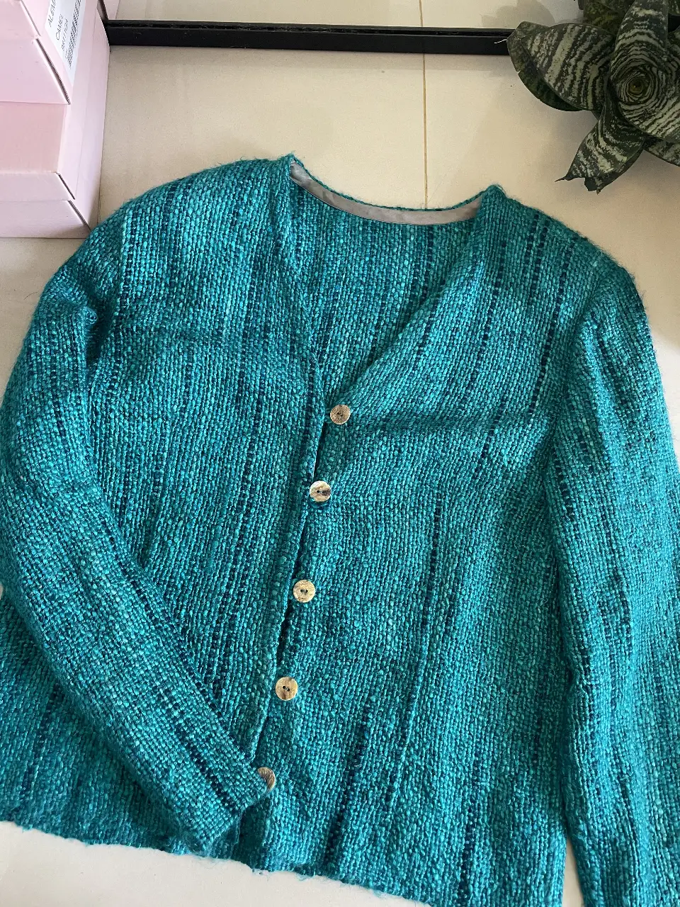 Cardigan tejido en color turquesa con botones dorados. Ideal para un look casual y abrigado.