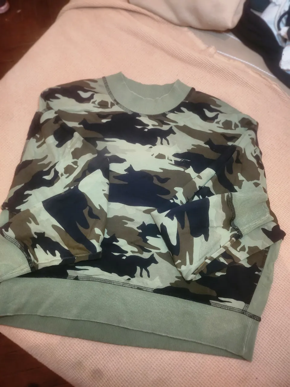 Buzo de algodón con estampa camuflada en tonos verdes, negros y crudos. Posee cuello redondo y puños de ribb.