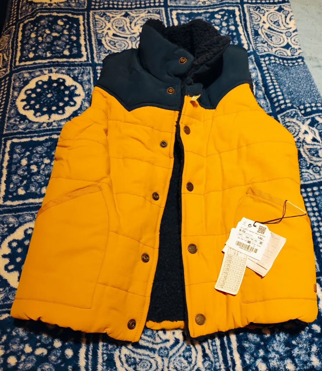 Chaleco Nuevo de Zara con corderito para niño, color amarillo con cuello y detalles en azul marino. Ideal para el invierno, con cierre de broches y bolsillos. 9-10 Años