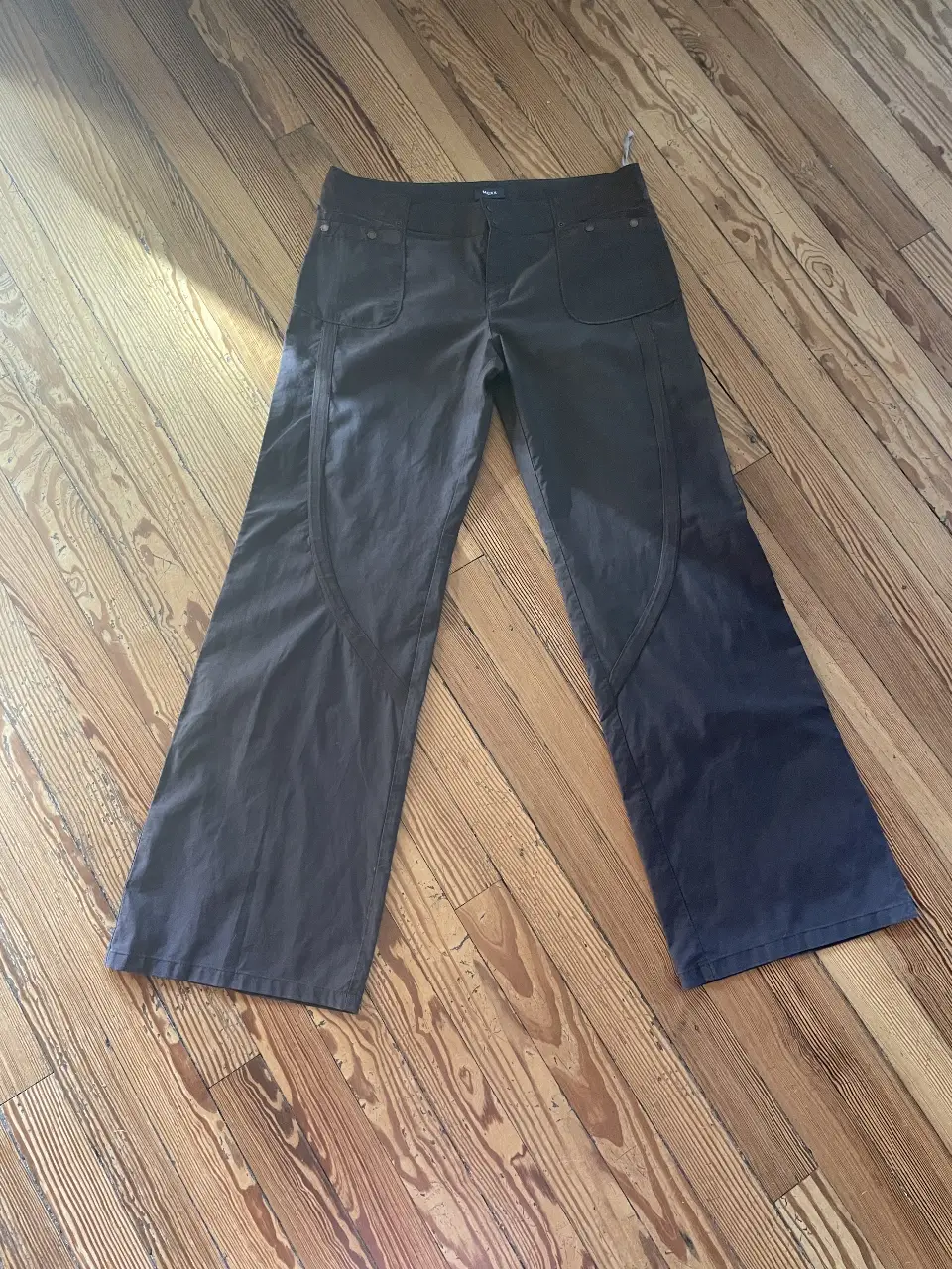 Pantalón de mujer, color marrón oscuro. Tiro medio y corte recto. Bolsillos delanteros y detalles de diseño en las costuras. 