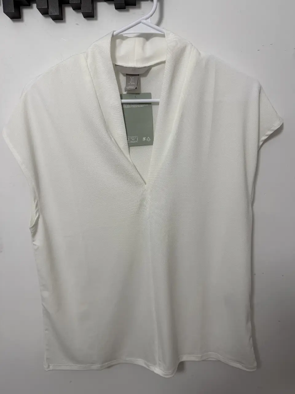Blusa blanca de mujer, con cuello en V y mangas cortas. Ideal para un look elegante y versátil.