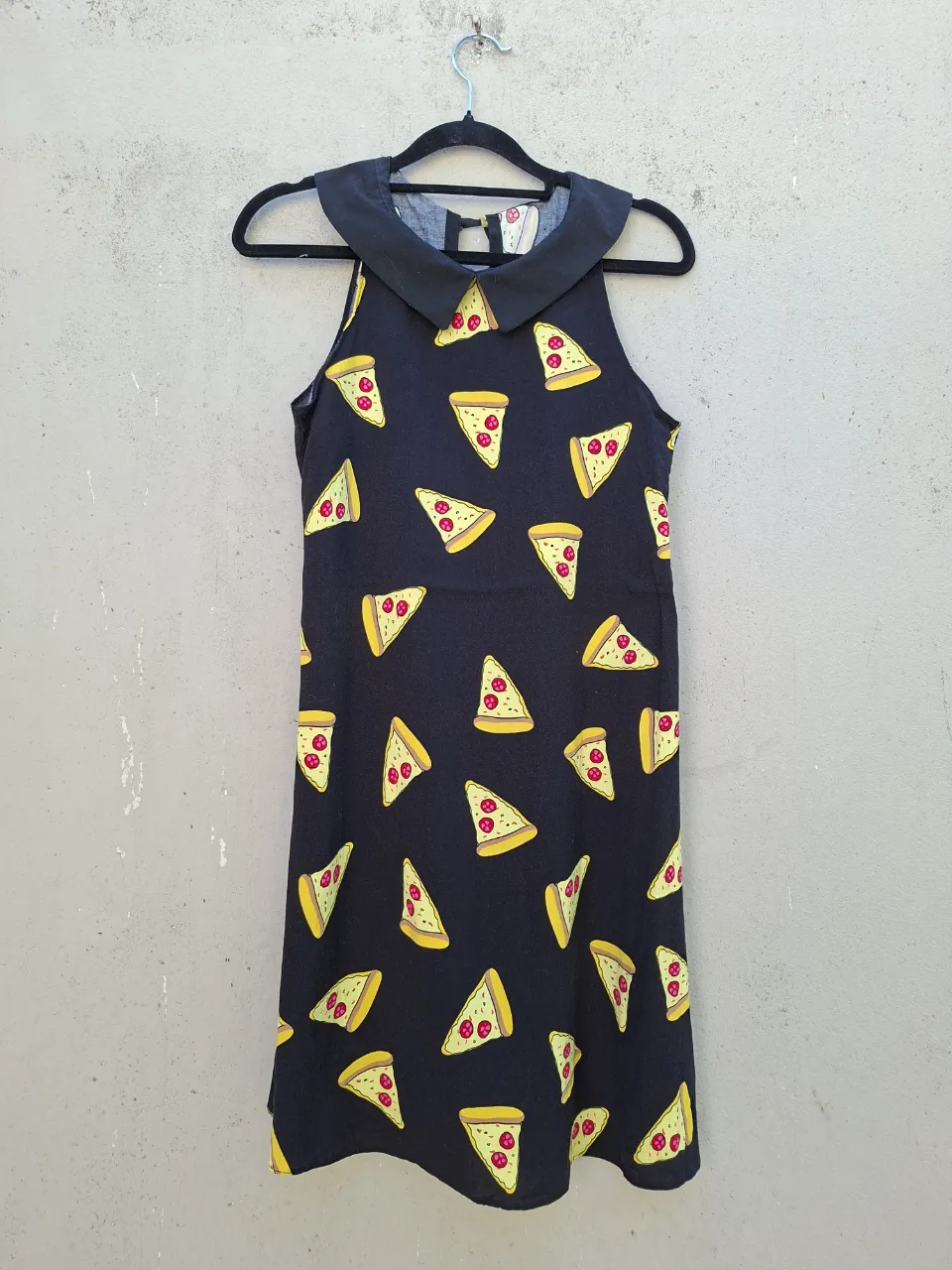 Vestido negro con estampa de fetas de pizza. Cuello redondo con solapa.