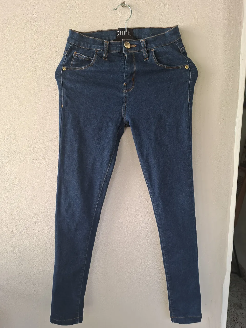 Jeans de corte chupín, color azul oscuro. Poseen bolsillos delanteros y traseros.