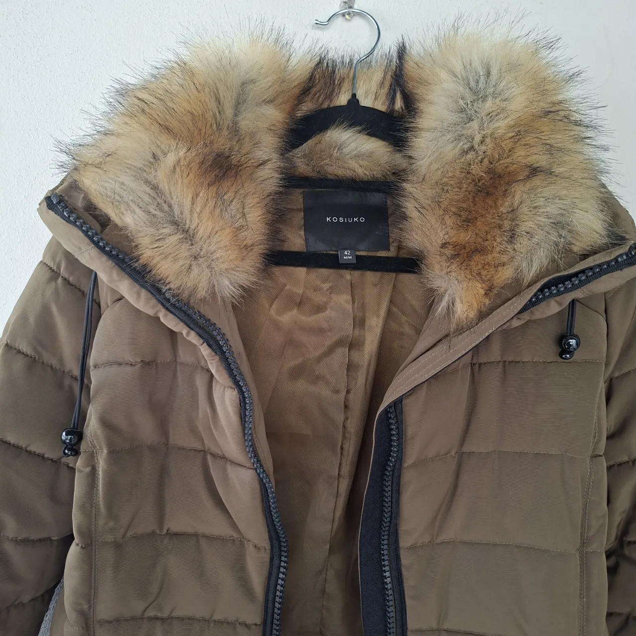 Campera de abrigo color oliva con capucha y detalles de piel sintética. Ideal para el frío, con cierre frontal y bolsillos con cierre. Un básico para tu guardarropa de invierno. Esta impecable, sin uso. Oportunidad.