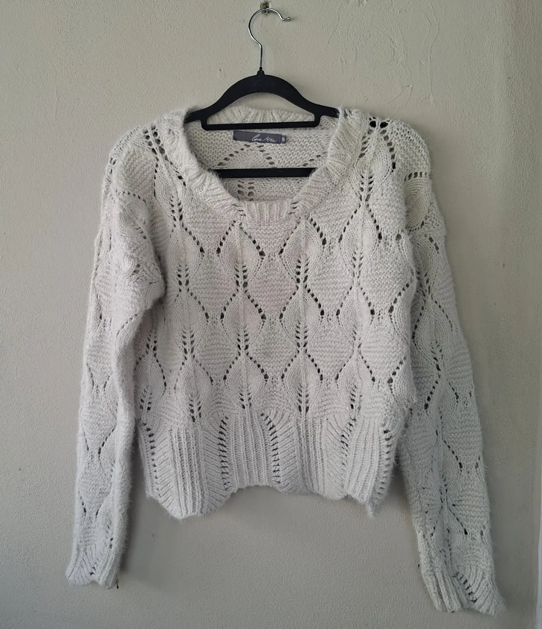 Sweater tejido de hilo color crudo, con un diseño calado muy delicado en forma de rombos. Tiene escote en V y mangas largas. Es perfecto para un look canchero y abrigado.