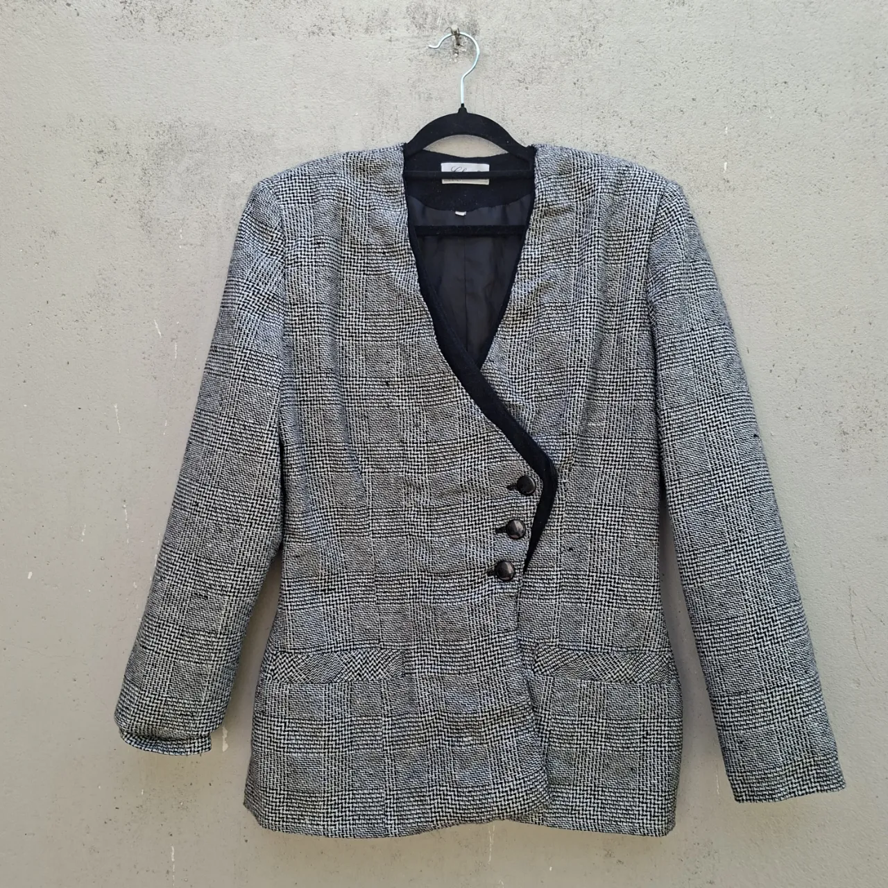Blazer italiano de vestir con un diseño a cuadros clásico en blanco y negro. Posee un corte entallado y solapa cruzada con botones que le dan un toque elegante. Ideal para looks formales o para elevar un outfit casual. 