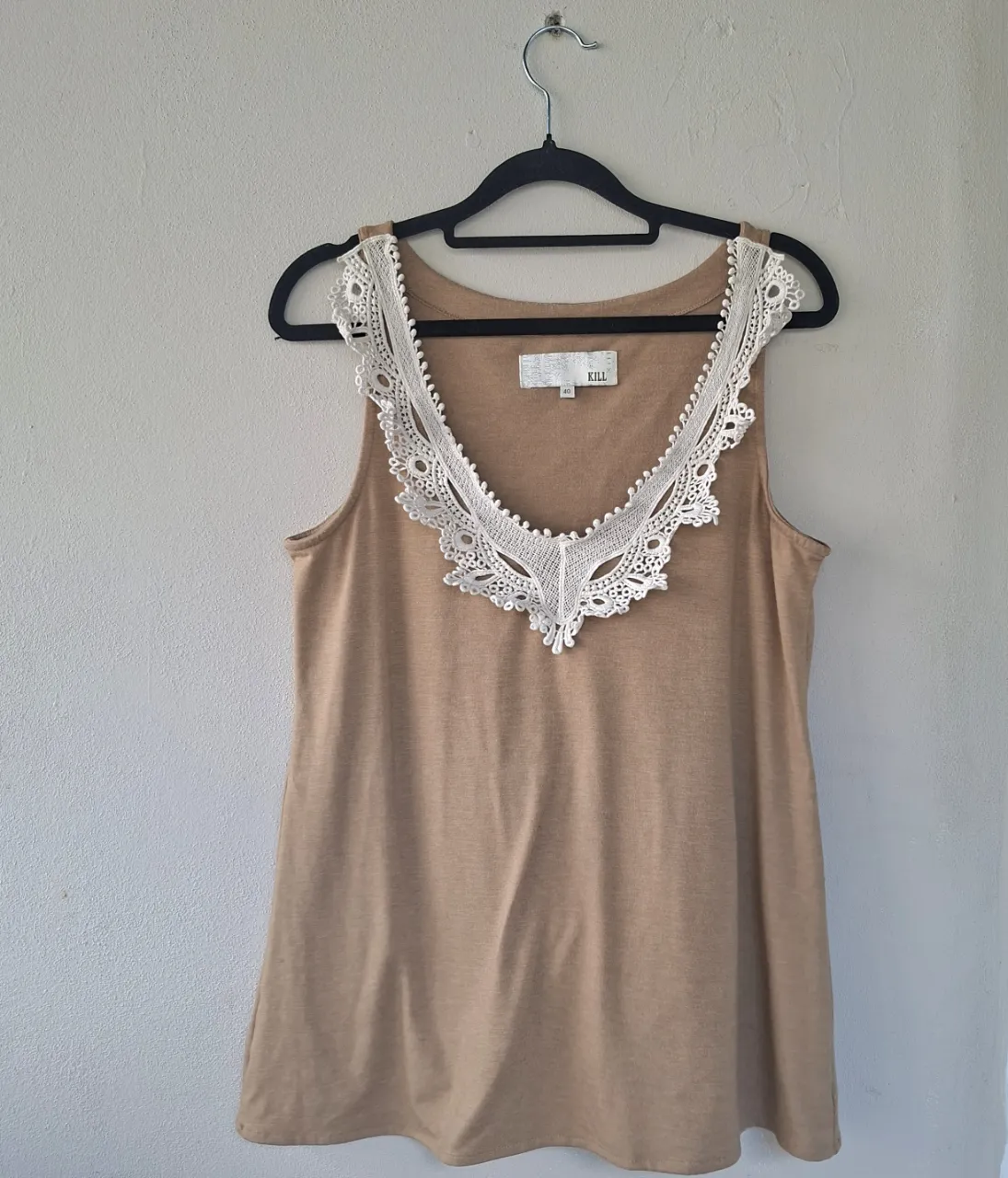 Musculosa color tiza con un delicado detalle de encaje blanco en el escote. Perfecta para un look casual y fresco.