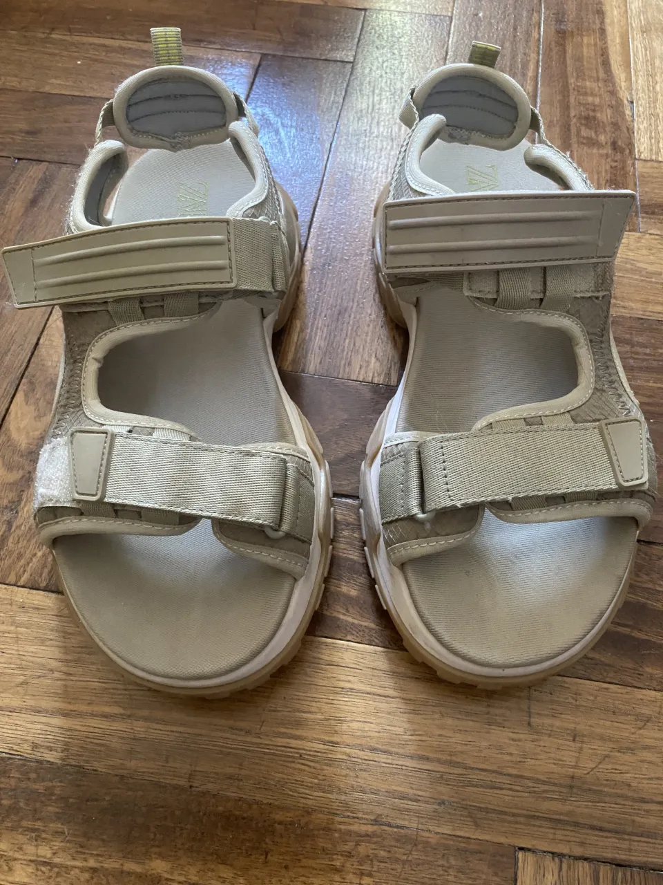 Sandalias color beige con tiras de velcro y suela gruesa.