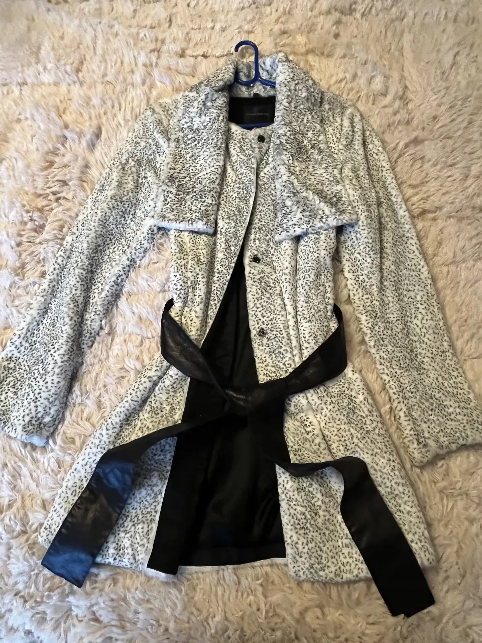 Tapado largo de piel sintética con estampado de leopardo en blanco y negro. Incluye cinturón negro para ajustar la cintura. Ideal para un look elegante y abrigado.
