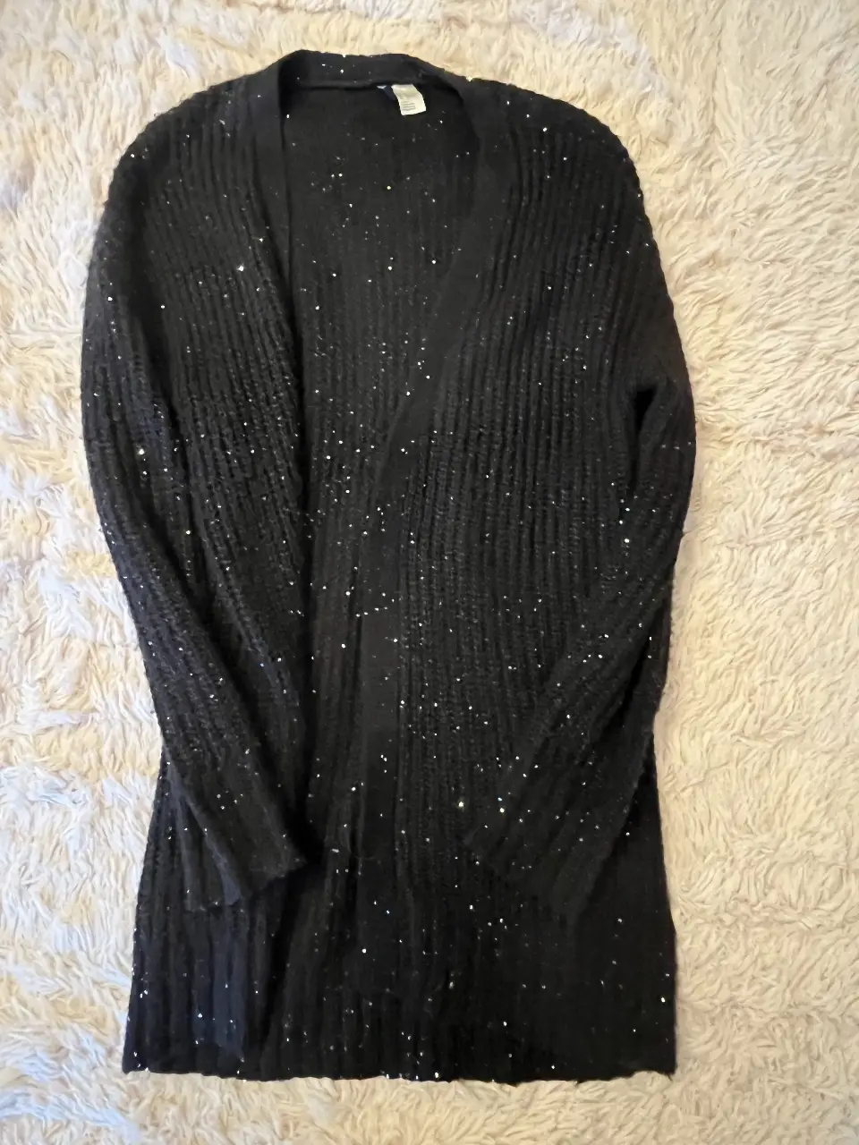 Cardigan negro de tejido grueso con lentejuelas plateadas. Ideal para un look de fiesta o para darle un toque especial a tu outfit casual. Marca Divided.