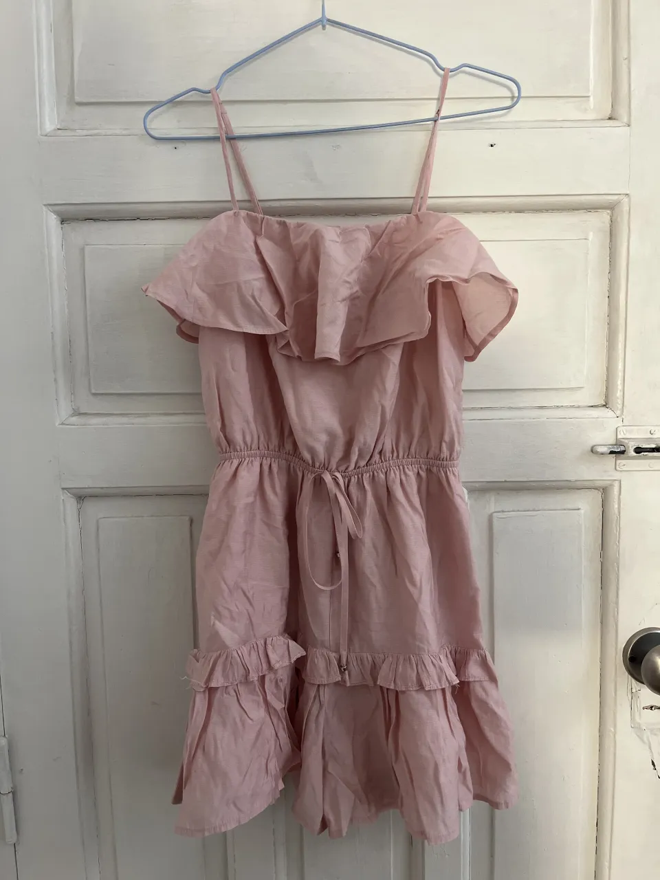 Vestido rosa con tirantes finos y volados en el busto y en la falda. Posee elástico en la cintura con un lazo para ajustar.