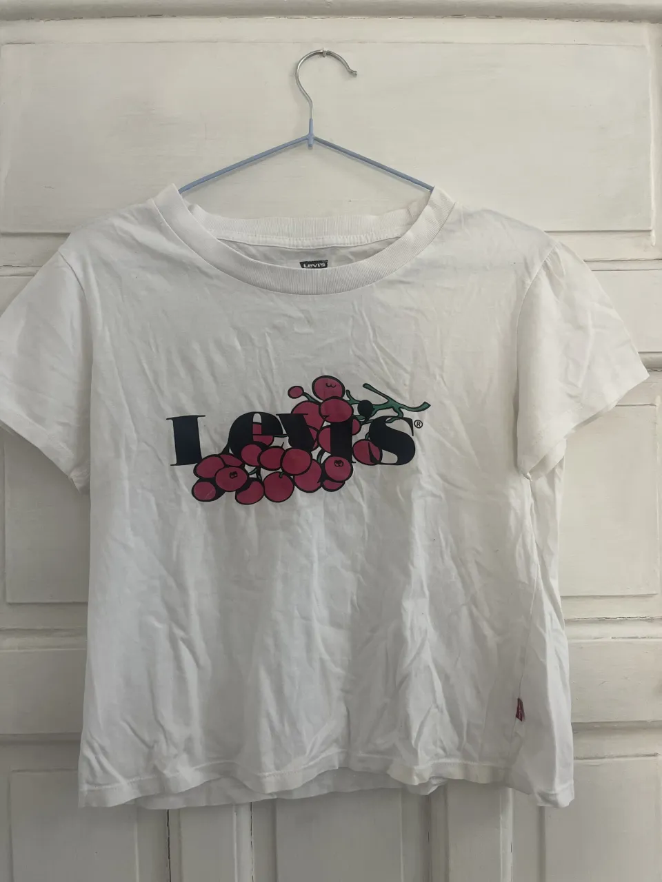 Remera blanca de manga corta con estampa de uvas y el logo de Levi's.