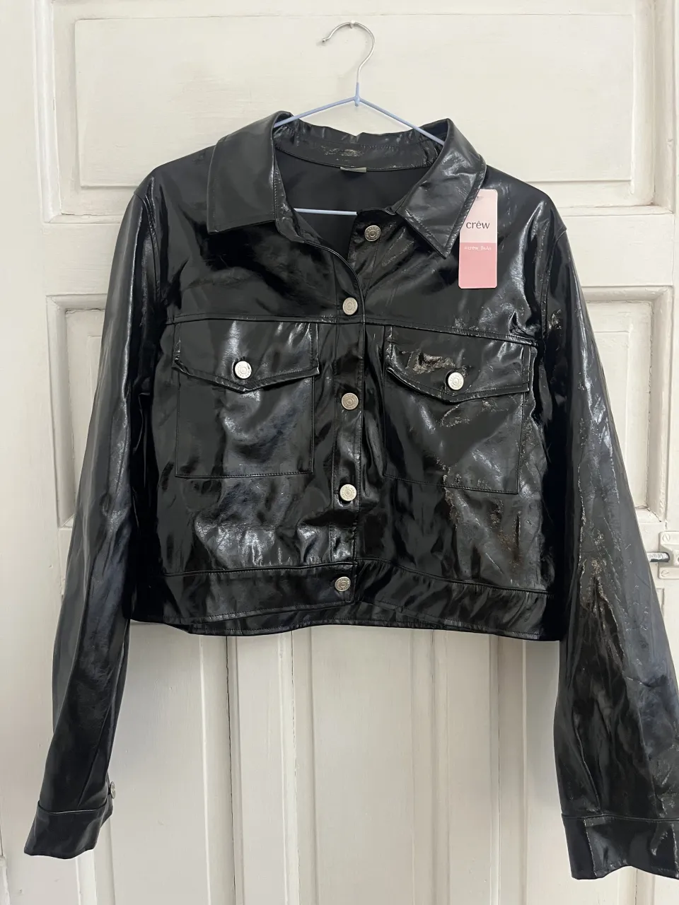 Campera negra de cuero sintético con botones al frente y bolsillos. Cuello camisero.