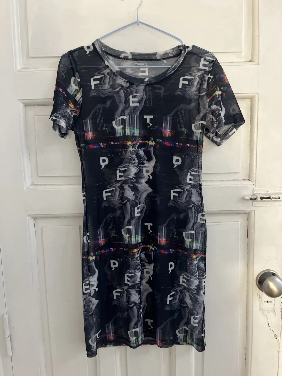 Remera de red negra con mangas cortas y cuello alto. Vestido estampado con figuras y letras.