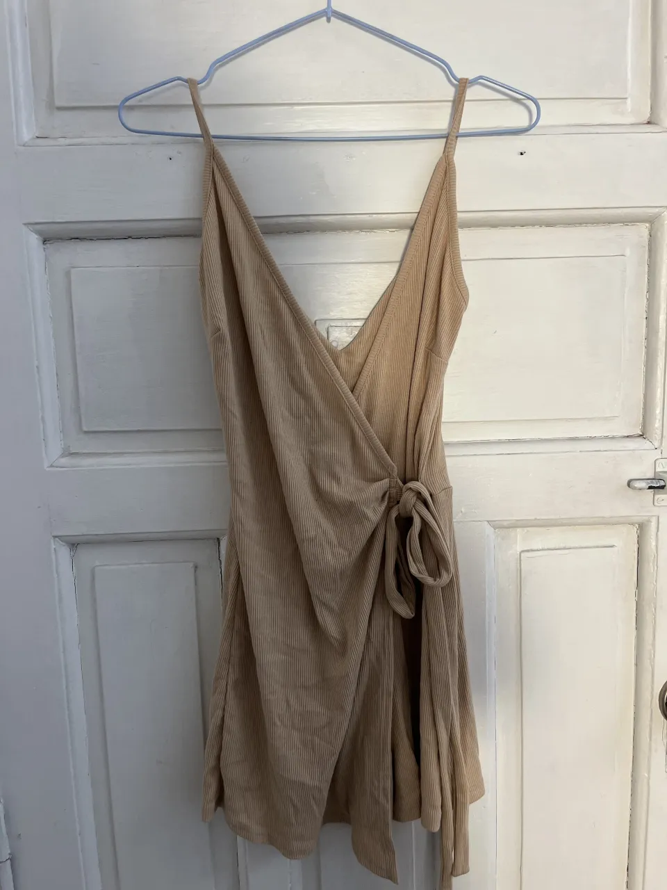 Vestido corto de tela acanalada con breteles finos y escote en V pronunciado. Posee un lazo para atar en la cintura.