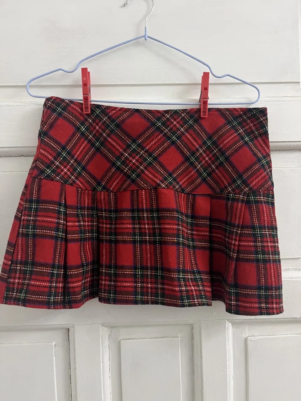 Pollera corta a cuadros escoceses en tonos rojos, negros y blancos. Posee un diseño plisado en la parte inferior.