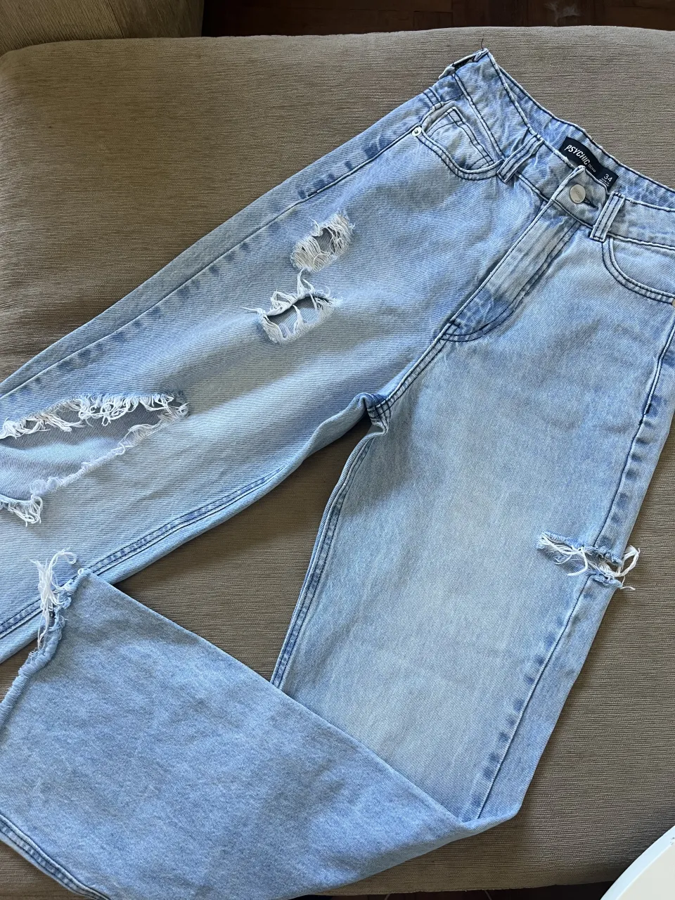 Jeans tiro alto de denim celeste con roturas y desgastes.