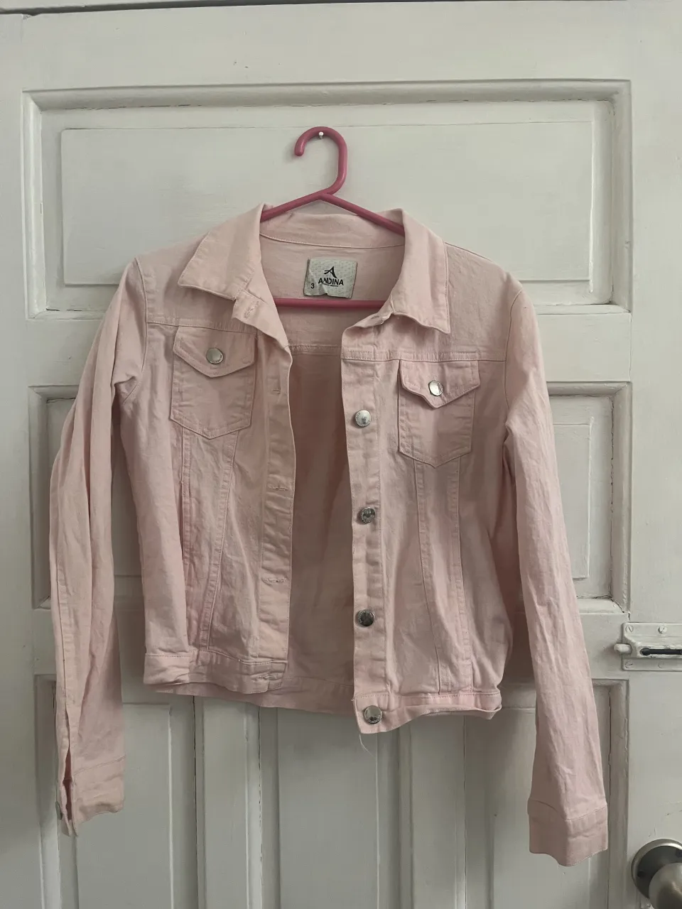 Campera de jean rosa con botones plateados y bolsillos frontales.