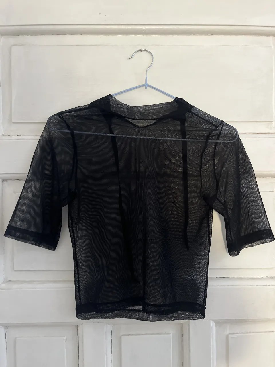 Remera negra de manga corta, con cuello redondo y tela de red transparente.